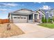 Front exterior of the home featuring a well-manicured lawn, stone accents, and a two-car garage at 11817 Phoebe St, Parker, CO 80134