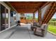 Covered patio boasts stone columns, ceiling fan, TV, and an outdoor seating area with stairs leading to the backyard at 11817 Phoebe St, Parker, CO 80134