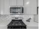 Close-up of modern kitchen appliances with a gas range, stainless steel microwave, and tiled backsplash at 17847 E 95Th Ave, Commerce City, CO 80022