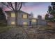 Charming two-story home featuring white brick, wood shutters and a well-manicured front yard at sunset at 709 S Alkire St, Lakewood, CO 80228