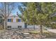 Two-story home with white brick and wooden shutters, complemented by mature trees in the front yard at 709 S Alkire St, Lakewood, CO 80228