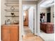 Hallway with a bar area, leads to the office with dark wooden desk and shelves at 7600 Landmark Way # 904, Greenwood Village, CO 80111