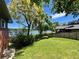 Expansive backyard featuring lush green lawn, mature trees, and a view of the tranquil lake at 2300 Willow Ln, Lakewood, CO 80215