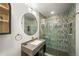 Stylish bathroom featuring a glass shower with striking tile surround and a modern vanity with a round illuminated mirror at 2300 Willow Ln, Lakewood, CO 80215