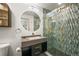 Modern bathroom with an illuminated round mirror, stylish vanity, and tiled glass shower in an elegant, renovated design at 2300 Willow Ln, Lakewood, CO 80215