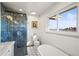 Bright bathroom featuring a walk-in shower with elegant marbled tile and a window offering a serene water view at 2300 Willow Ln, Lakewood, CO 80215