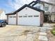 Exterior of a two-story home featuring a three-car garage with white doors and brick accents at 19987 E Belleview Pl, Centennial, CO 80015