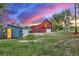 Charming red barn with a vibrant sunset backdrop and additional outbuildings on a sprawling property at 13183 N 95Th St, Longmont, CO 80504