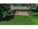 Landscaped backyard featuring green grass, mature trees, deck and patio at 1705 Stonehenge Dr, Lafayette, CO 80026