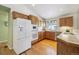 L-shaped kitchen with wood cabinets, hardwood floors, and a breakfast bar at 1894 S Marshall Cir, Lakewood, CO 80232