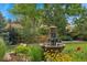 Serene backyard with a tiered stone fountain surrounded by lush greenery and flowers at 3765 E Easter Dr, Centennial, CO 80122