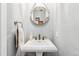 Chic powder room with a pedestal sink, a round mirror, and soft lighting at 3765 E Easter Dr, Centennial, CO 80122