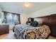 This main bedroom features a dark wood headboard, a patterned bedspread, and decorative window treatments at 5541 Killarney Ct, Denver, CO 80249