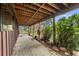 Covered back porch with wooden beams and concrete flooring surrounded by mature greenery at 32171 Lodgepole Dr, Evergreen, CO 80439