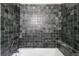 Bathroom shower featuring dark tile and updated hardware at 32171 Lodgepole Dr, Evergreen, CO 80439