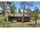 Exterior view of home surrounded by mature trees and a wooden deck at 32171 Lodgepole Dr, Evergreen, CO 80439