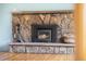 Close-up of stone fireplace with wood-burning insert and a decorative basket of wood at 32171 Lodgepole Dr, Evergreen, CO 80439