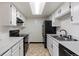 Galley kitchen features sleek black appliances and bright white marble countertops at 942 S Walden St # 206, Aurora, CO 80017