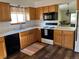 A well-lit kitchen with wooden cabinets, black appliances, wood-style flooring, and a colorful striped rug at 9724 W Euclid Dr, Littleton, CO 80123