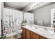 Updated bathroom with double sink vanity, large mirror, and shower with floral curtain at 6227 Shenandoah Ave, Firestone, CO 80504