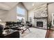 Bright and airy living room featuring a stone fireplace, vaulted ceilings, and comfortable black leather sofas at 6227 Shenandoah Ave, Firestone, CO 80504