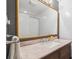 Bathroom features a large gold mirror and updated vanity with a marble countertop and white sink at 806 S Jersey St, Denver, CO 80224