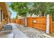 The backyard has a pebble-lined walkway adjacent to the house's AC Unit and a wooden fence at 8845 W 81St Dr, Arvada, CO 80005