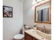 A bathroom with a framed painting over the toilet, and an unframed mirror over the sink basin at 8845 W 81St Dr, Arvada, CO 80005