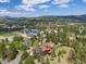 Scenic aerial view of a home near community buildings, surrounded by lush trees and mountains in the background at 2140 Torrey Pine Dr, Evergreen, CO 80439