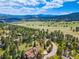 Stunning aerial view of a home nestled in a scenic mountain landscape with lush trees and expansive meadows at 2140 Torrey Pine Dr, Evergreen, CO 80439