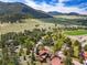 Expansive aerial view of a neighborhood surrounded by green trees, fields, and mountains on a sunny day at 2140 Torrey Pine Dr, Evergreen, CO 80439