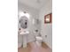 A stylish half-bathroom featuring a pedestal sink, modern toilet, decorative mirror, and tiled floors at 1800 Vantage Pkwy, Berthoud, CO 80513