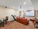 Spacious basement featuring a leather couch, a projector screen, and brown carpet at 8501 Hackamore Rd, Littleton, CO 80125