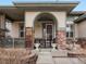 Inviting front porch with brick columns, decorative plants, and an arched entrance at 8501 Hackamore Rd, Littleton, CO 80125