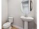Neat powder room featuring pedestal sink, round mirror, and hardwood floors at 1825 Morgan Dr, Erie, CO 80516