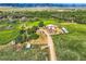 Aerial view of a large rural property with multiple buildings, surrounded by lush greenery and rolling hills at 11475 Us Highway 85, Littleton, CO 80125