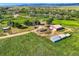 Gorgeous aerial view of a multi-acre property featuring lush green fields, a house, and multiple outbuildings at 11475 Us Highway 85, Littleton, CO 80125