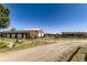 Exterior of a rural property with multiple outbuildings and a gravel driveway, set against a clear blue sky at 11475 Us Highway 85, Littleton, CO 80125