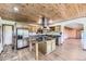 Open kitchen with a wood ceiling, stainless steel appliances, and center island with granite counter at 11475 Us Highway 85, Littleton, CO 80125