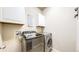 Bright laundry room with modern washer and dryer, cabinets for storage, and a tile floor at 24289 E Brandt Ave, Aurora, CO 80016