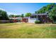 View of a large lawn, brick exterior, an outdoor dining set with an umbrella, and a wooden fence at 5945 W Colgate Pl, Denver, CO 80227