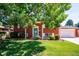 Charming red brick home featuring a well-maintained lawn, mature trees, and a welcoming blue front door at 5945 W Colgate Pl, Denver, CO 80227
