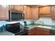 Kitchen featuring wood cabinets, updated appliances, laminate countertops and a modern stainless steel microwave at 5945 W Colgate Pl, Denver, CO 80227