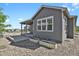 Back exterior with covered patio, stone beds, and view of neighborhood homes at 5723 Berry Ridge Way, Castle Rock, CO 80104