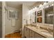 Well-lit bathroom featuring a double vanity with granite countertop, artwork, and mirrors at 4192 Timbervale Dr, Evergreen, CO 80439