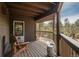 Spacious covered deck with wood floors, chairs, and tree views at 4192 Timbervale Dr, Evergreen, CO 80439