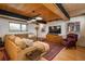 Open living room with wood ceiling, large sectional couch and a comfortable leather armchair by the TV at 4192 Timbervale Dr, Evergreen, CO 80439