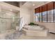 Elegant bathroom featuring a soaking tub, glass-enclosed shower, and neutral tile at 1435 Wazee St # 403, Denver, CO 80202