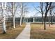 Scenic view of community tennis courts accessible by a paved path lined with trees and black metal fence at 1808 Southard St, Erie, CO 80516