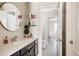Bathroom with a round mirror, sleek vanity, quartz countertop, and well-organized shelves at 14537 Honolulu Cir, Parker, CO 80134